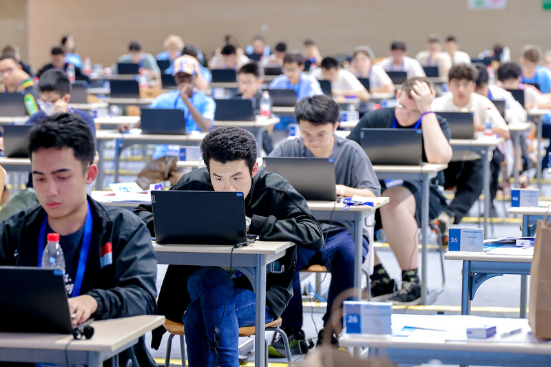 Student in an exam hall focusing looking at laptop screen